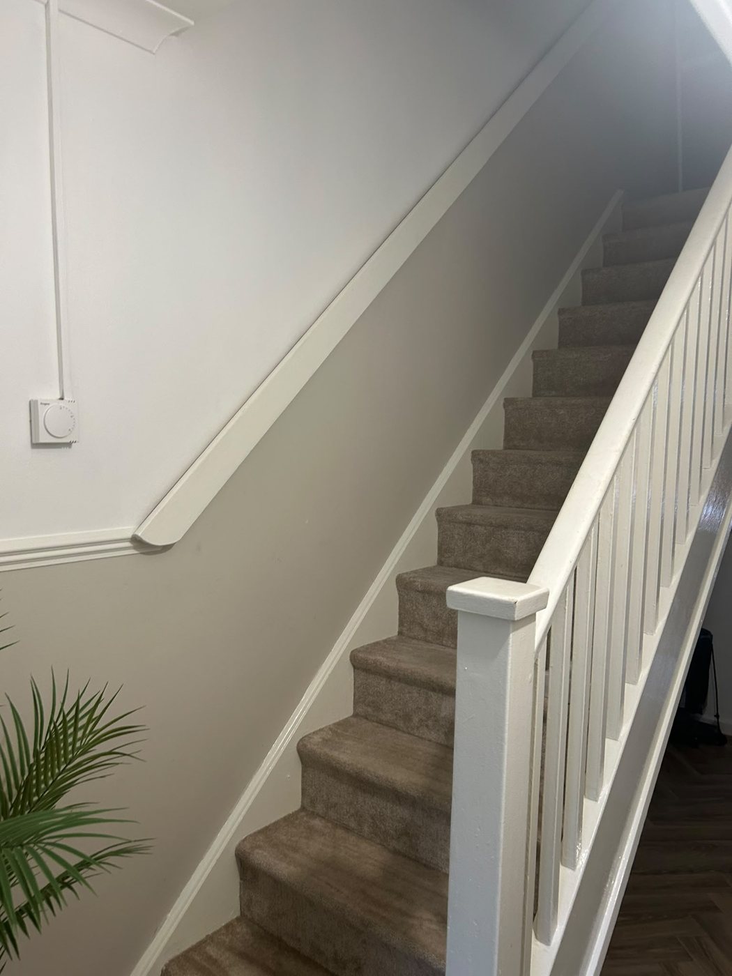 Staircase and landing painted in soft grey with a white banister and spindles, in a Hurst Green home