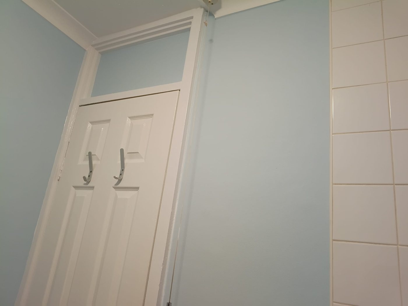 White panelled door and frame in a bathroom with pale blue walls, Little Common